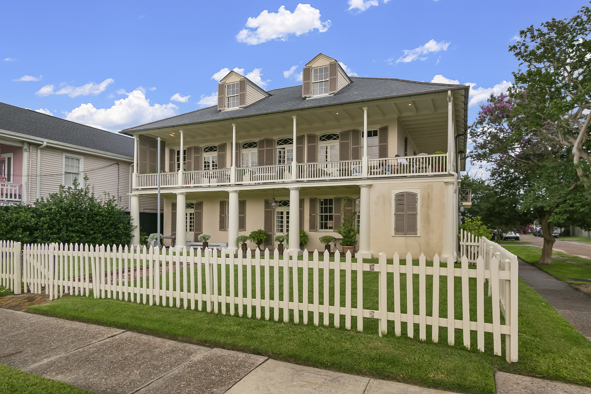 Raised two-story center-hall New Orleans home with double galleries and a white picket fence in Lakeview